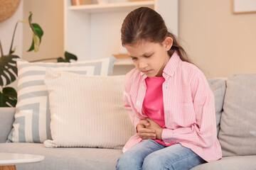 Teenage girl with appendicitis sitting on sofa at home