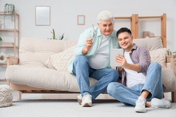 Young man with his father using tablet computer at home