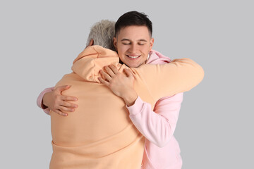 Young man with his father hugging on light background