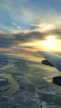 Aerial view from airplane from window. Beautiful sunbeams, sinrise, plane is landing