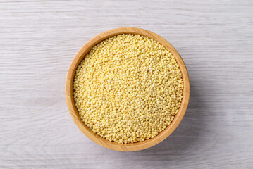 Organic yellow millet grain in wooden bowl on white table, Healthy food ingredient, Top view