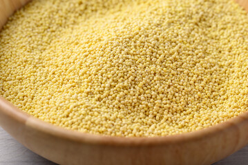 Organic yellow millet grain in wooden bowl, Healthy food ingredient