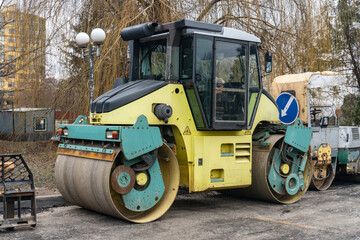 Fototapeta premium Yellow asphalt paver parked on gravel construction site