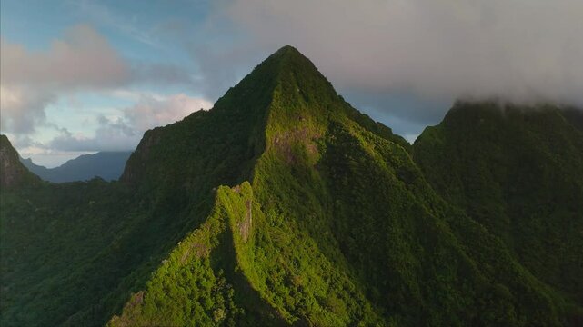 Breathtaking beauty of green tropical island mountains rising above the clouds at sunset, dramatic and awe inspiring landscape. Remote wild nature paradise, exotic summer travel. Aerial drone shot