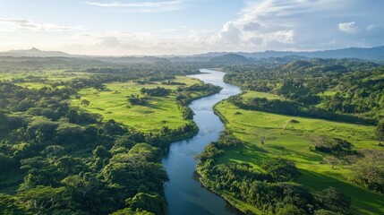 Fototapeta premium Aerial view of a meandering river flowing through lush green landscape.