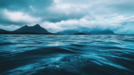Dramatic ocean view with mountains under stormy clouds.