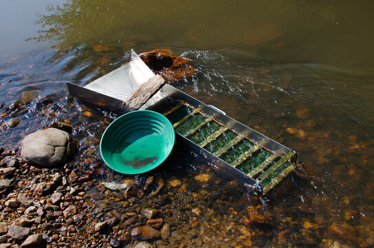 Gold panning and mining in riverbed. prospecting for gold using sluice box and gold pan. Gold panning and mining in riverbed. Fun and adventure of recreational activity of gold panning and gem mining.
