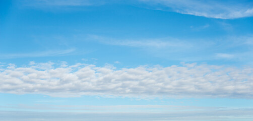 panorama blue sky background with small clouds. White clouds move in the sky in the sunshine. Amazing.