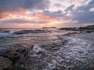 Colourful Coastal Sunrise with Waves on Rocks