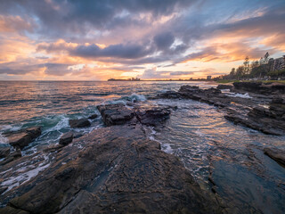 Fototapeta premium Colourful Coastal Sunrise with Waves on Rocks