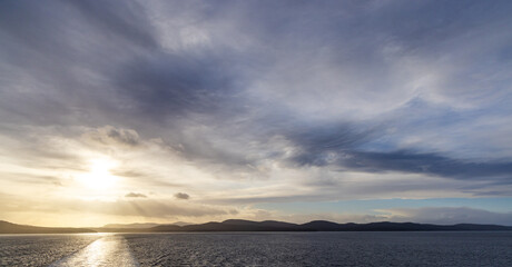 Fototapeta premium Sunset Over Coastal Waters and Distant Mountain Range