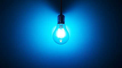 A glowing blue light bulb illuminating a wall in a dark setting.