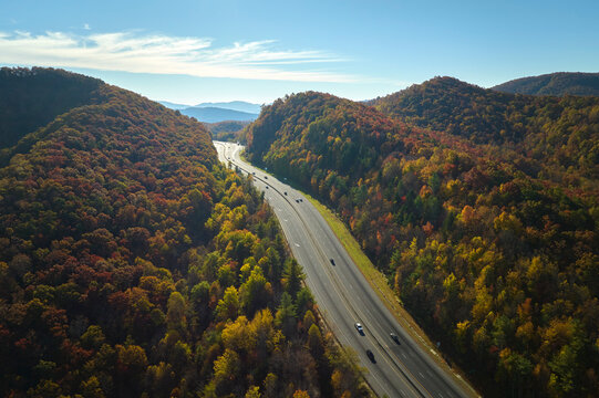 View from above of I-40 freeway route in North Carolina leading to Asheville thru Appalachian mountains with yellow fall woods and fast moving trucks and cars. Interstate transportation concept