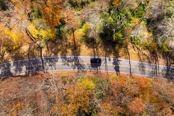 Obraz premium Winding mountain road in autumn woods. Appalachian mountains in North Carolina with yellow forest trees at fall season. Beauty of autumnal nature