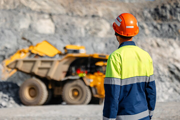 Work engineer control loading of gold ore by excavator into large quarry yellow truck. Concept open...