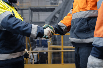 Industry workers shaking hands on background workplace concentrating plant of copper and gold....