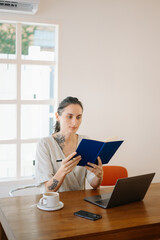 Freelancer woman working remotely in cafe, with laptop, coffee, and cellphone. Casual outfit, productivity, and urban lifestyle captured in vibrant detail