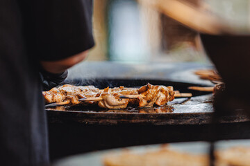 Cook grills chicken steaks and pork ribs open fire. Turns meat over with tongs. Street food concept