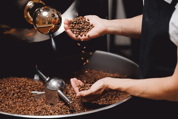Closeup view of roasted coffee beans in mans hand. Food industry business coffeeshop