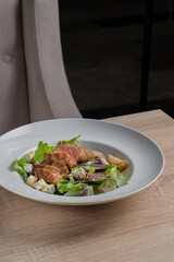 Baked piece of meat among green salad and vegetables on table in restaurant
