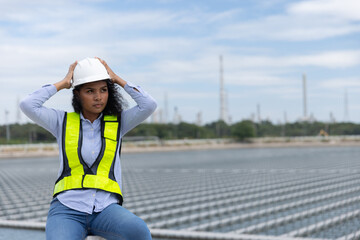  A female engineer wearing a safety helmet and high-visibility vest stands at a solar installation site