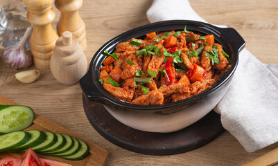 Baked meat in tomato sauce with herbs in a ceramic dish.
