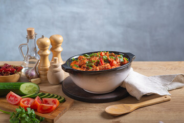 Baked meat in tomato sauce with herbs in a ceramic dish.