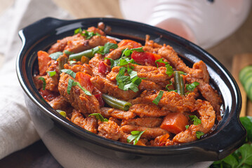 Baked meat in tomato sauce with herbs in a ceramic dish.