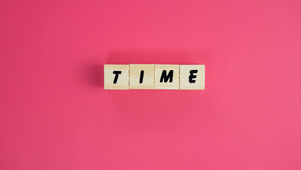 The word TIME written on wooden letter cubes over a vibrant pink background, time management and punctuality concept