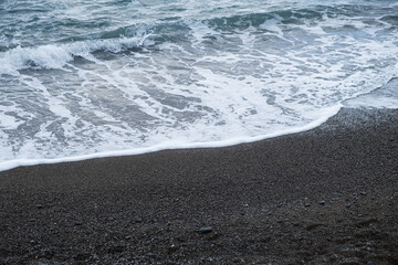 Turquoise sea in close-up in bright sunlight. Colorful tropical background. The concept of summer vacation, travel. Clear blue water, small waves lapping at the sandy shore. The texture of the beach