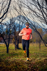 Athletic man running in autumn forest trail