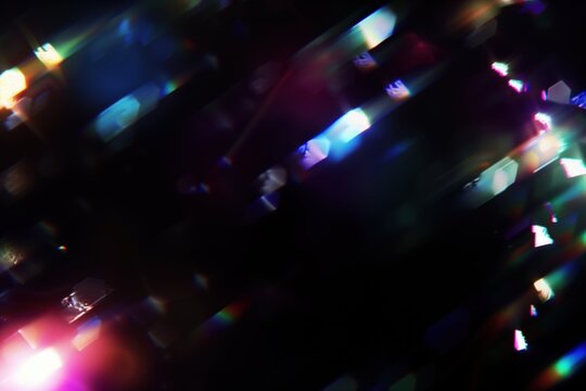 Colorful light burst with lens flares on dark background. Modern digital projects, abstract design, technology themes. Blurry cinematic sparkling particles in the air, festive light effect