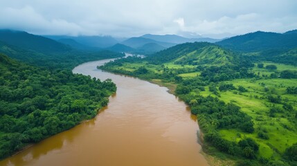 Aerial view of lush green river valley and mountains shrouded in clouds after rainfall showcasing serene natural beauty and vibrant landscapes