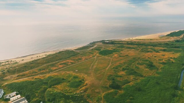 Drone flying over the green shore of Lowestoft beach towards the sea on a cloudy day in England