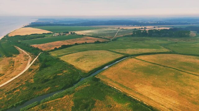 Drone flying over the green fields of Lowestoft beach on a sunny day with misty skies in England