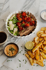 Delicious grilled steak served with crispy fries and roasted tomatoes on a white plate