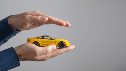 Caucasian businessman showing yellow toy car.