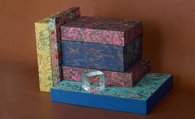 A set of marble-paper-covered books or boxes on a soft brown background. 