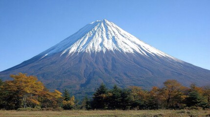 Fototapeta premium Majestic snow-capped mountain peak with autumn foliage in foreground under clear blue sky.