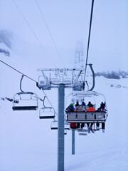 Chairlift carrying skiers into the clouds on a snowy day in Val Thorens.