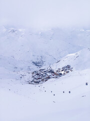 Val Thorens covered in snow, surrounded by the French Alps under a cloudy sky. A peaceful winter scene.