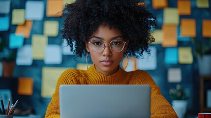 A woman with curly hair is sitting at a desk with a laptop in front of her. Generative AI