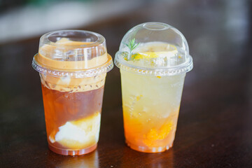 Close up glass of ice iced cool yuzu espresso, iced emaricano with coconut water on wooden table of a coffee shop summer terrace, menu photography.