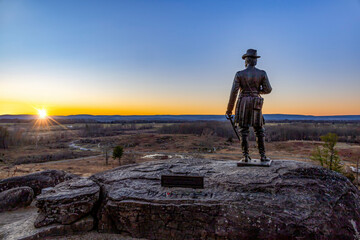 A breathtaking sunset over Gettysburg Battlefield from Little Round Top with the statue of General Warren.