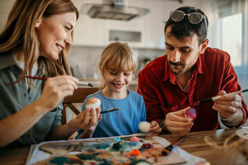 Family teamwork as they dip Easter eggs into dye and add colorful patterns