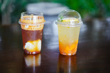 Close up glass of ice iced cool yuzu espresso, iced emaricano with coconut water on wooden table of a coffee shop summer terrace, menu photography.