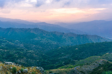 highland mountain landscape of beautiful sunset or sunrise with nice mountain peaks and slopes, green and golden hills and majestic cloudy sky on background