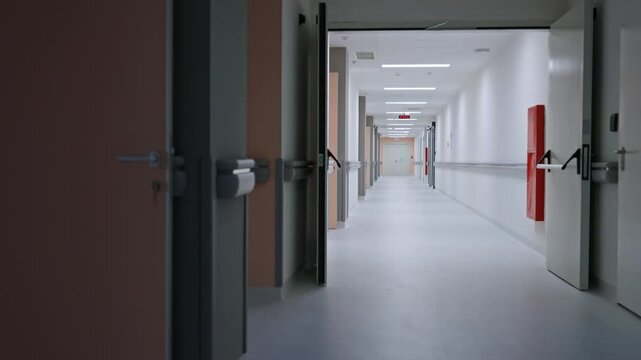 Long empty hospital corridor with closed and open doors, bright lighting, and clean design. Concept of healthcare facilities, sterile environments, or hospital infrastructure
