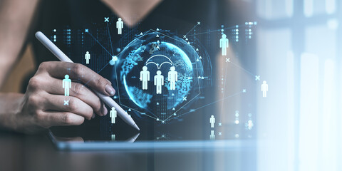 Hand holding stylus pen interacting with digital tablet displaying social network icons and global connections on bright background.