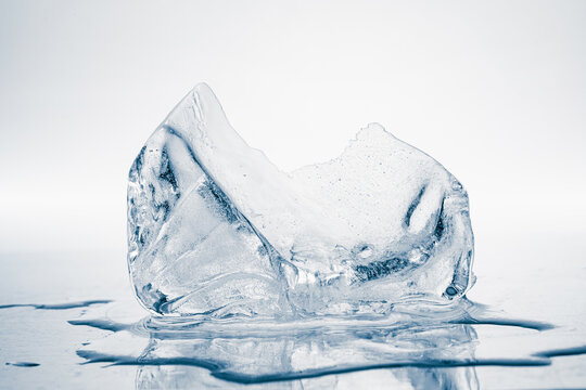 Melting piece of ice on a white background with reflection.